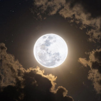 Яркая полная луна освещает небо и облака