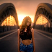 Девушка в джинсовых шортах на фоне моста.