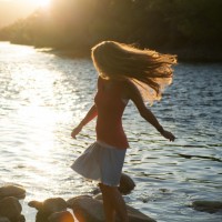 Девушка резвится на камнях у берега небольшой реки