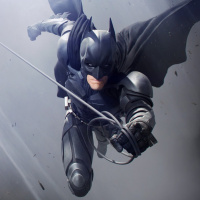 Бэтмен с напряжённым лицом прыгает с верёвкой в руке