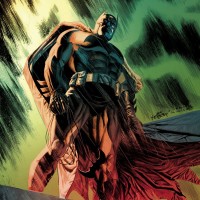 Бэтмен с верёвкой в руке смотрит вниз с крыши.