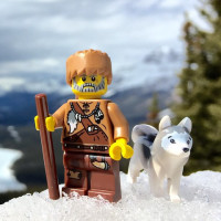 Лего минифигурки охотника и собаки хаски на фоне гор