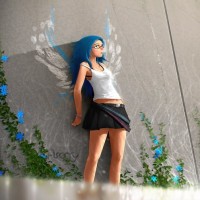 Девушка с синими волосами стоит у стены с нарисованными крыльями