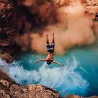Падающий в воду мужчина с большой высоты с расставленными в сторону руками