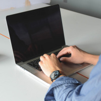 Мужские руки на клавиатуре ноутбука с выключенным экраном
