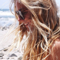 Улыбающаяся девушка в солнцезащитных очках на фоне моря