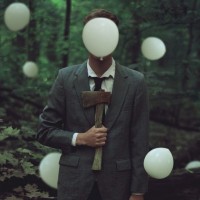 Мужчина с топором стоит в лесу среди белых воздушных шариков