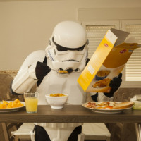 Штурмовик из Звёздных воин за столом ест хлопья и читает упаковку них