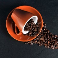 Опрокинутая кружка кофе, из которой высыпались кофейные зерна.