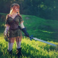 Девушка стоит в траве с мечом в руке в костюме Линка из игры Зельда