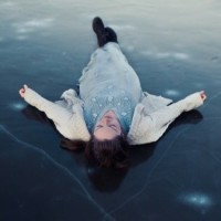 Девушка лежит на спине на льду, который пошёл трещинами
