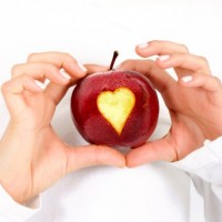 Девушка держит в руках яблоко с вырезанным сердечком